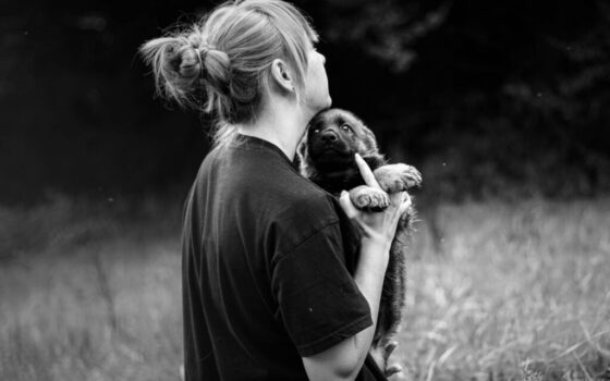 grayscale photo of person holding puppy